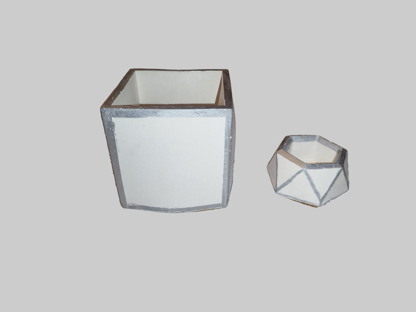 Two geometric pen holders on a light gray background
