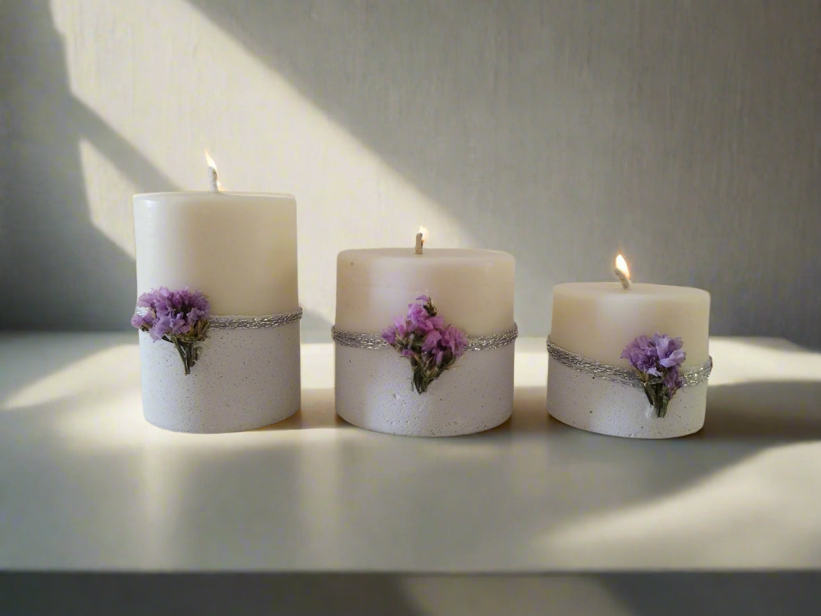 Σετ τριών λευκών κεριών με τσιμεντένια βάση πάνω σε τσιμεντένια επιδάνεια