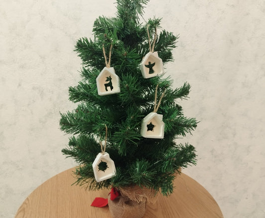 Small decorated Christmas tree with house ornaments on a wooden table