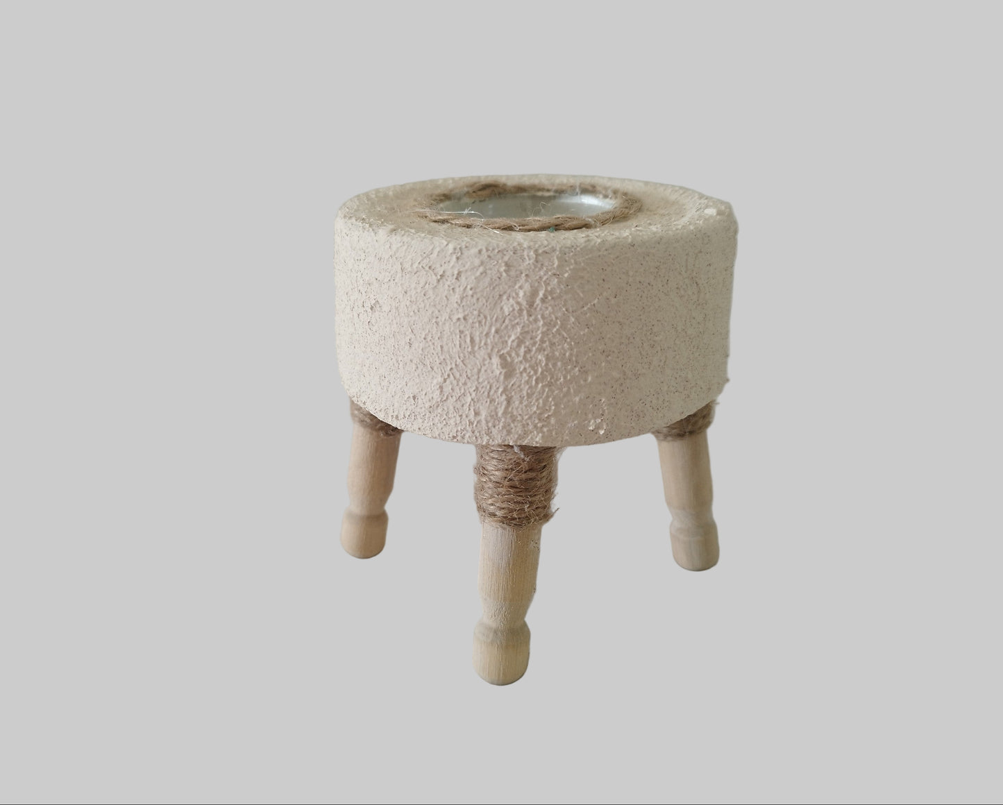 Στρογγυλό τσιμεντένιο ρεσώ με ανάγλυφη υφή και ξύλινα ποδαράκια σε γκρι φόντο απο την κάτω πλευρά