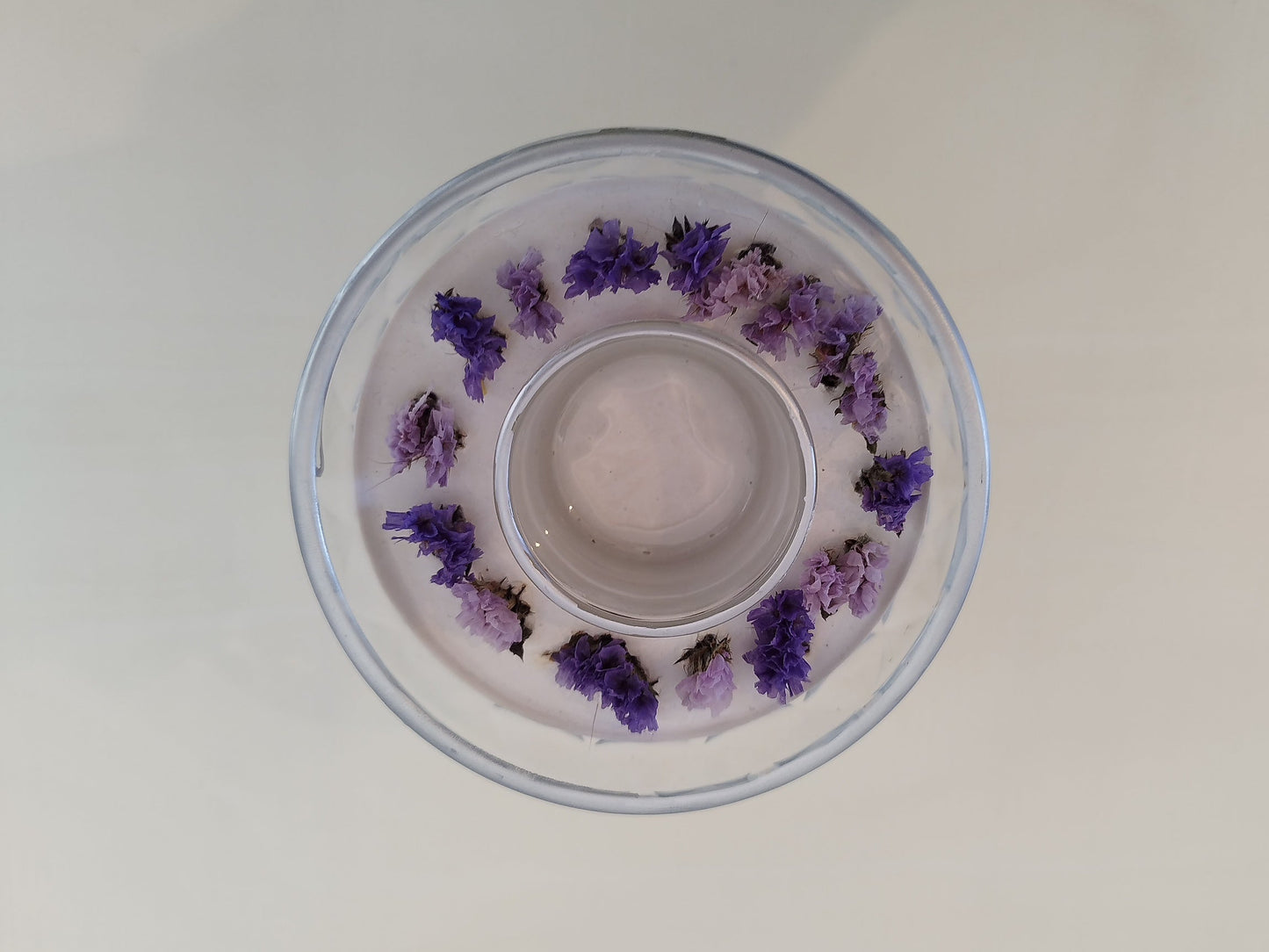 Clear container with purple flowers on a white background