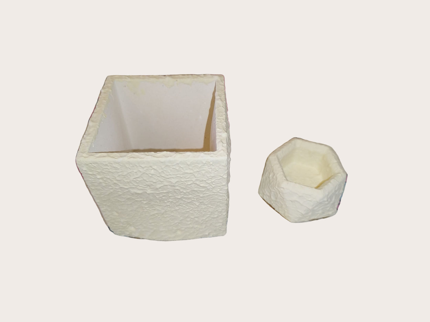 Two textured white containers on a light gray background