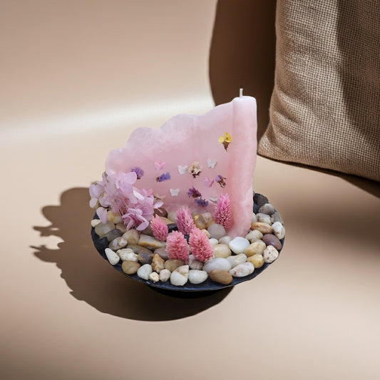 Ροζ παστέλ κερί με πεταλούδες & αποξηραμένα λουλούδια δίπλα σε ένα μαξιλάρι