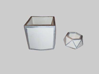 Two geometric pen holders on a light gray background