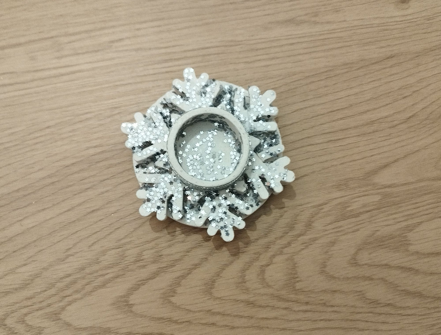 Decorative silver snowflake candle holder on a wooden table