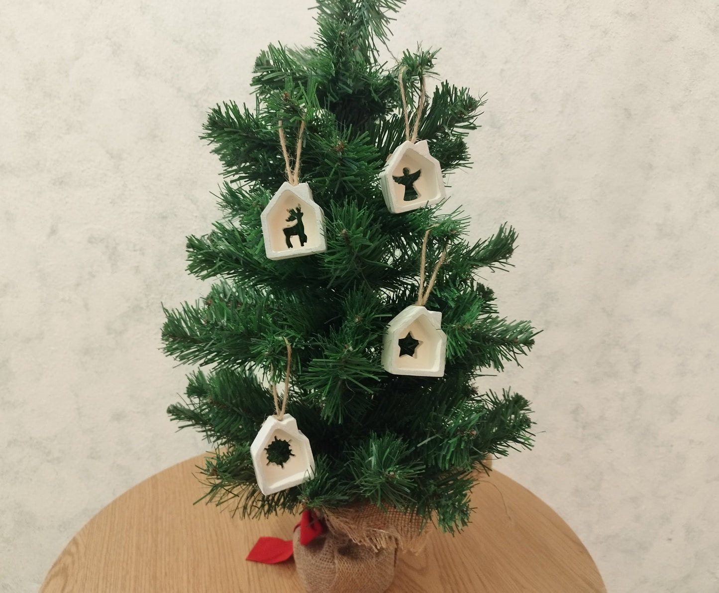 Small decorated Christmas tree with house ornaments on a wooden table