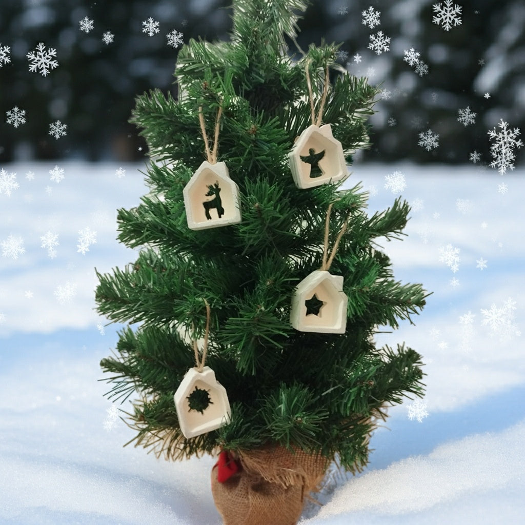 Small decorated Christmas tree with house ornaments on a snowy background