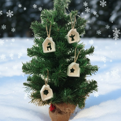 Small decorated Christmas tree with house ornaments on a snowy background