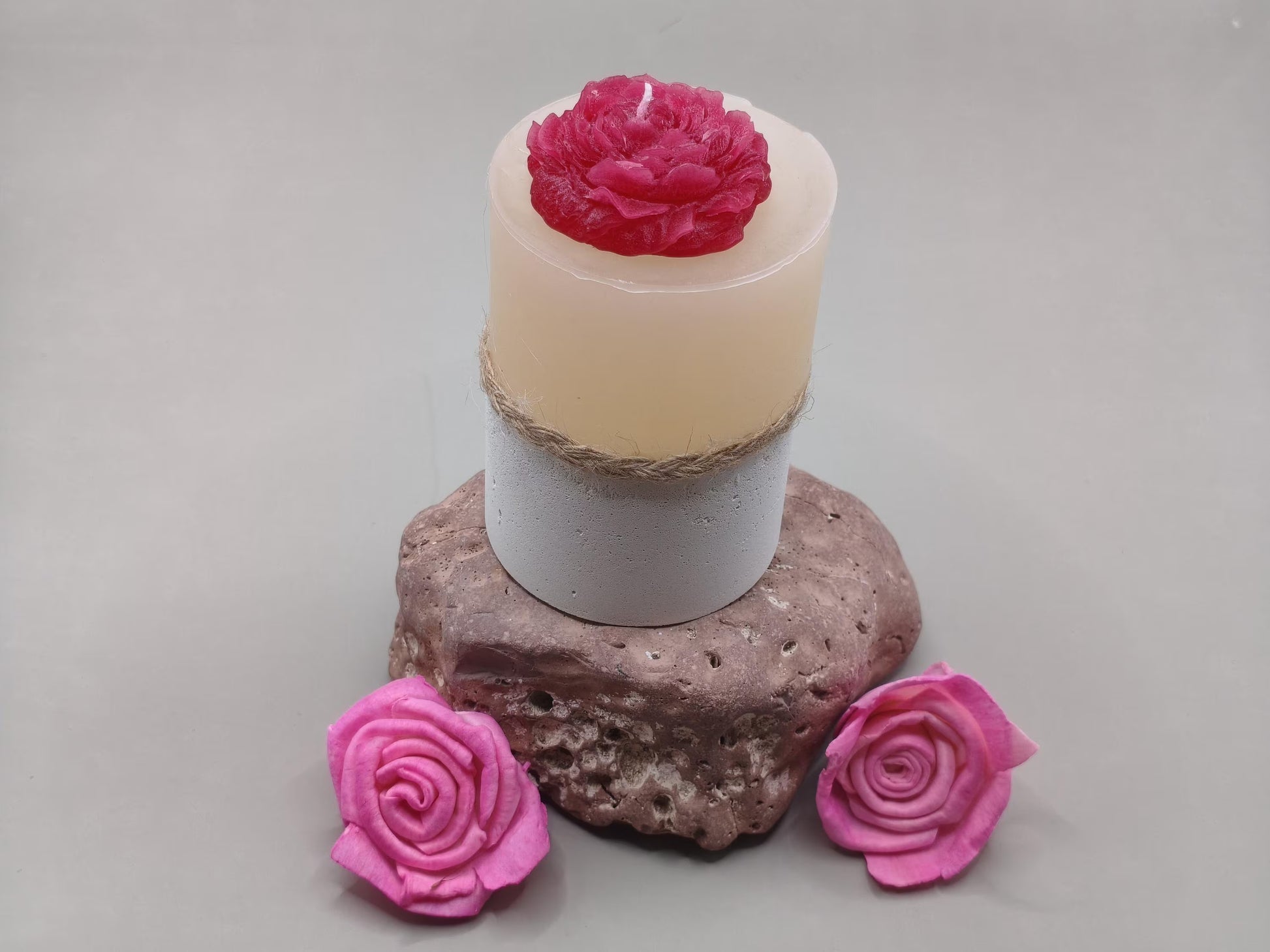 Χειροποίητο κερί με κόκκινο τριαντάφυλλο και τσιμεντένια βάση πάνω σε πέτρα