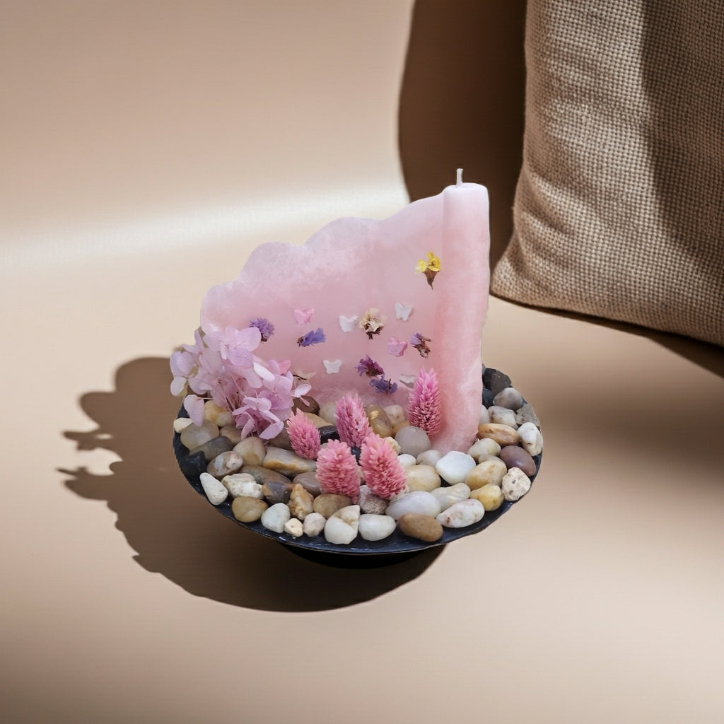 Ροζ παστέλ κερί με πεταλούδες & αποξηραμένα λουλούδια δίπλα σε ένα μαξιλάρι