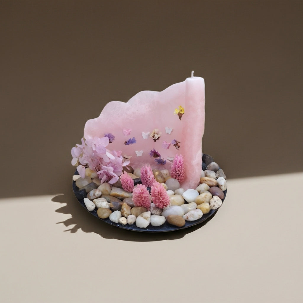 Ροζ παστέλ κερί με πεταλούδες & αποξηραμένα λουλούδια πάνω σε μια γκρι επιφάνεια