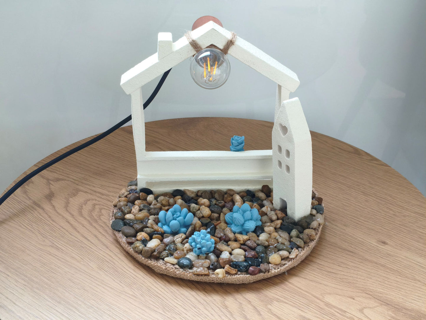 Φωτιστικό με τσιμεντένια σπιτάκια πάνω σε ξύλινο τραπέζι