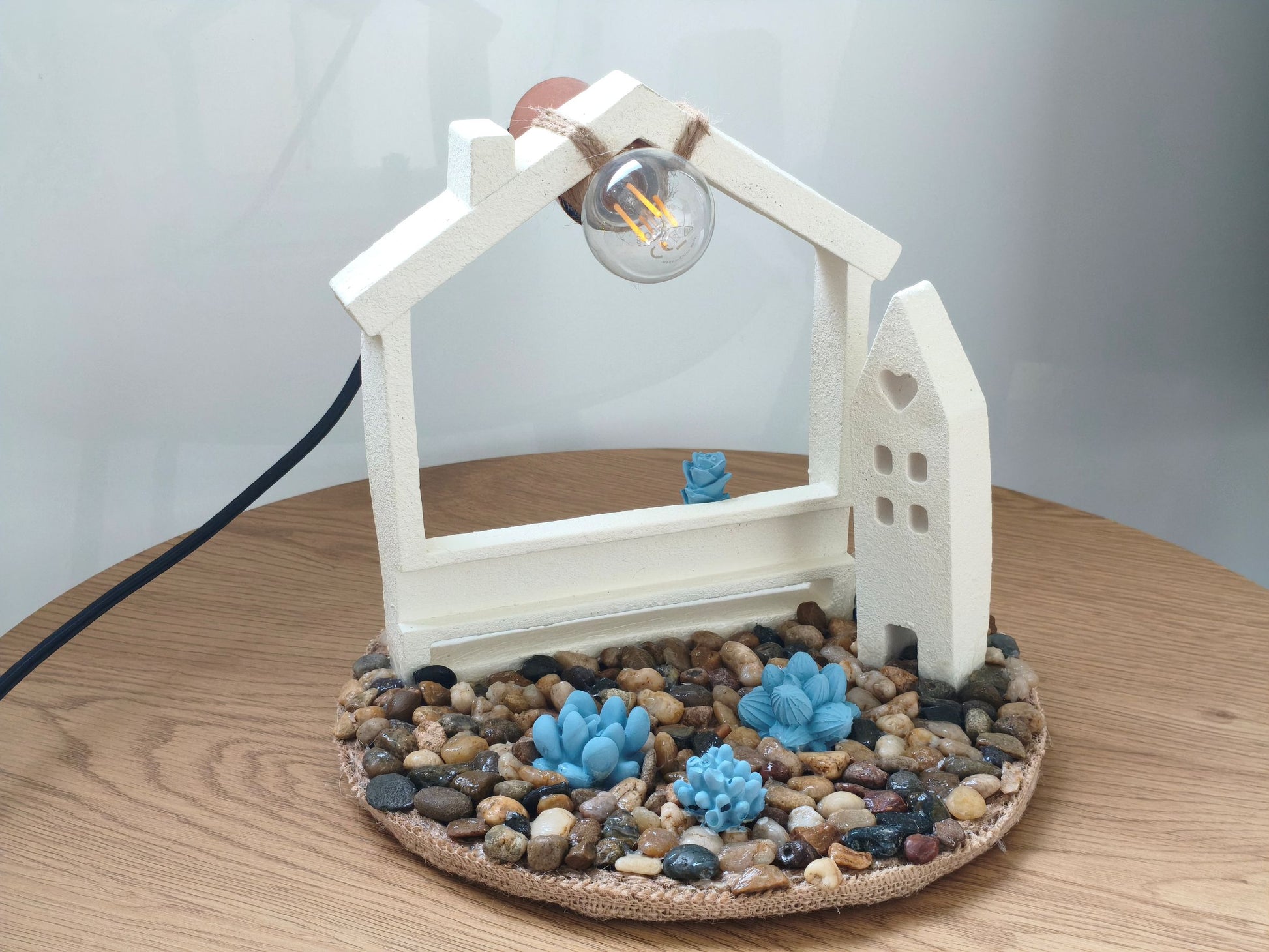Φωτιστικό με τσιμεντένια σπιτάκια πάνω σε ξύλινη επιφάνεια
