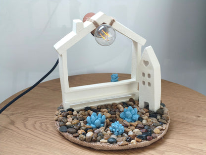 Φωτιστικό με τσιμεντένια σπιτάκια πάνω σε ξύλινη επιφάνεια