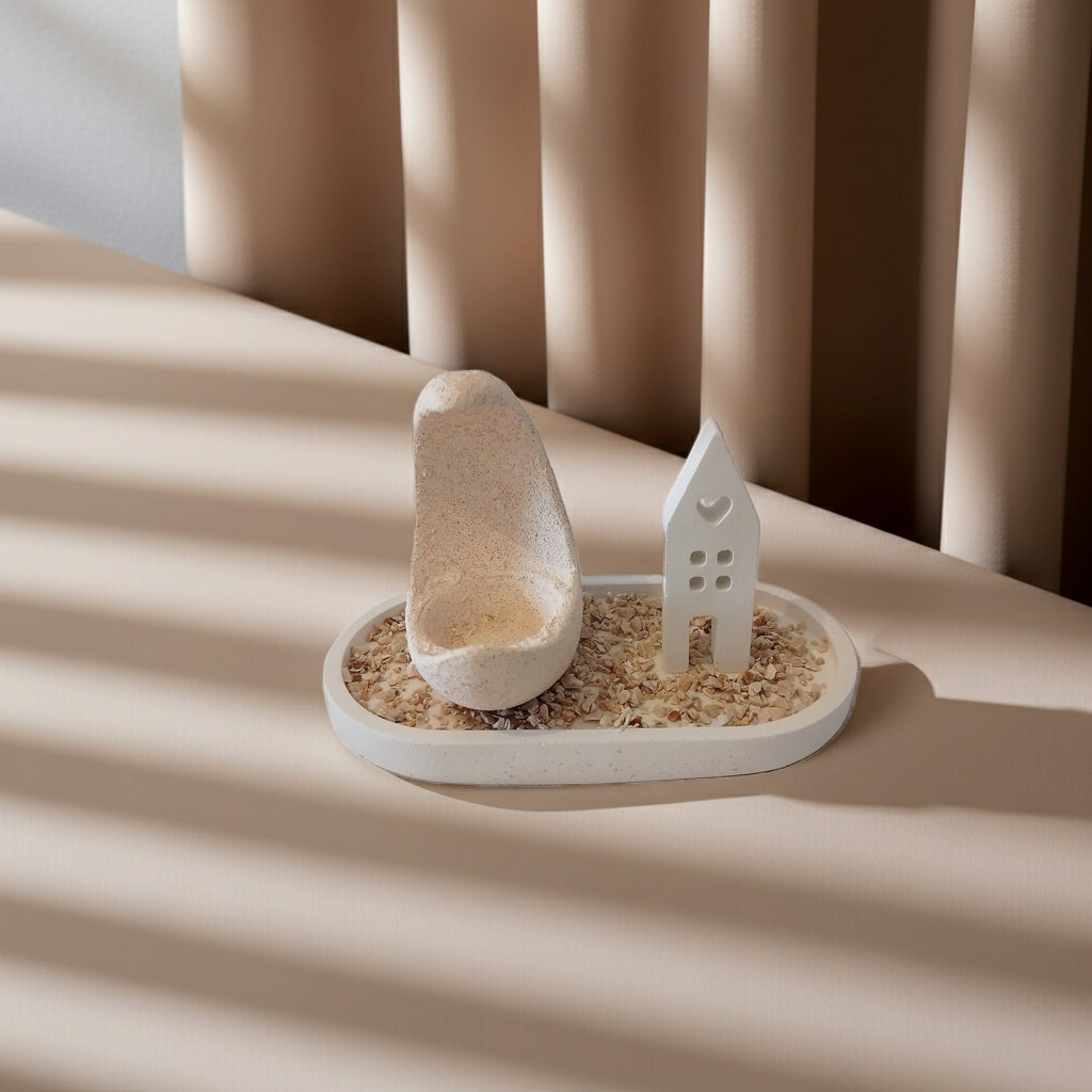 Τσιμεντένιο πιατάκι με ρεσώ και μικρό σπιτάκι από τσιμέντο πάνω σε τραπέζι