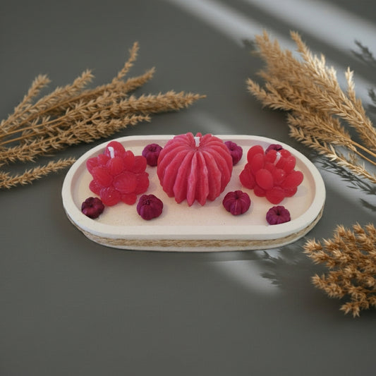 Decorative candles shaped like berries on a white plate with dried plants in the background