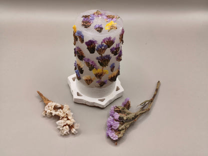 Διακοσμητικό κερί με αποξηραμένα λουλούδια σε τσιμεντένια βάση σε γκρι φόντο